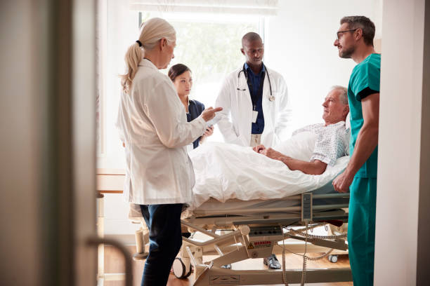 medical team on rounds meeting around bed of senior male patient